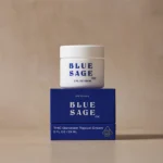 Blue Sage Original THC Dominant Topical Cream (2 FL OZ / 59 ML) white jar sitting atop its royal blue product box against a beige background.